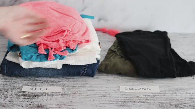 hand sorting and moving some fashion clothes from a Keep to a Declutter pile