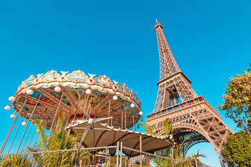 28 July 2019, Paris, France: Retro romantic carousel on the background of the Eiffel tower at sunset