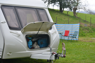 Caravan with door open as people set up camp. 