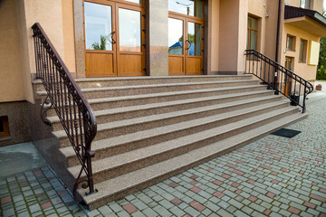 Detail of a house facade. New granite stairs with metal railings.