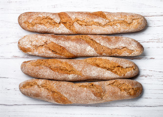 Freshly baked homemade cereal baguettes with oatmeal and flax seed on a white wooden table. Selective focus.