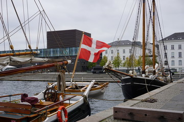Fototapeta na wymiar dänische Flagge auf Schiff in Kopenhagen zwischen Neubau und Altbau