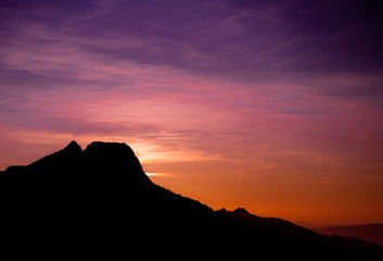Romantic purple and orange sunset over the high Tatra mountains with dense mist and long sun rays
