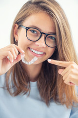 Dental invisible braces or silicone trainer in the hands of a young smiling girl. Orthodontic concept - Invisalign