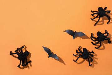 Halloween border of spiders and bat on orange paper. Flat lay, top view. Creative Halloween Day composition.