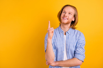 Photo of cheerful checkered beaming smiling guy pointing up at empty space wearing blue checkered...