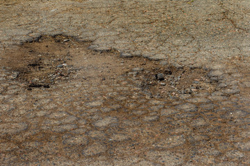 Damaged road, cracked asphalt. Asphalt with potholes and spot. Very bad asphalt road with large cracks. Scary technology in road construction. Numerous dangerous failures patching of road