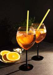 Two glasses of aperol spritz cocktail with orange slices on black background.