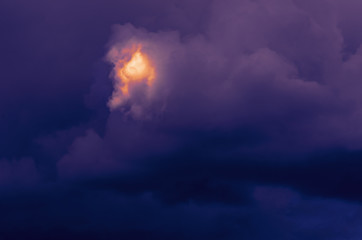 Dramatic Storm Clouds with a Shining Golden Spot. Light in the Darkness, Flash in the Night Concept.