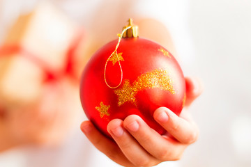 a boy holds out his hand with a red Christmas ball