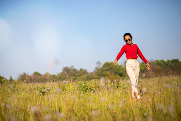 Hipster Asian woman in red and sunglasses on white flower and grass field