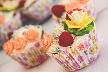Close up view on decorated party cupcakes. Colorful cupcake flower icing and raspberry decoration. 