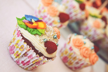 Close up view on decorated party cupcakes. Colorful cupcake flower icing and raspberry decoration. 