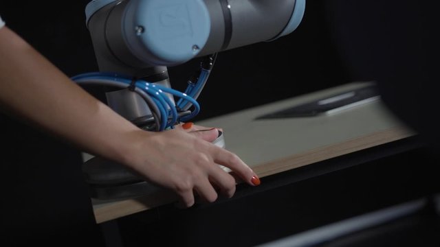 Woman's hand with long red fingernails assembles a robotic end of arm tool