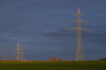 Hochspannungsmasten und Stromleitung im Abendlicht