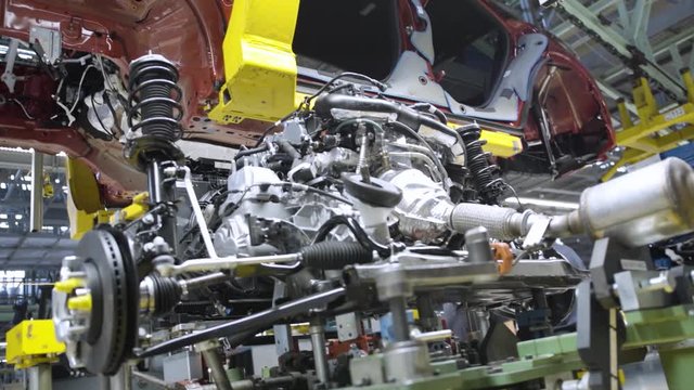Close up slow motion of a car engine inside an automotive production plant. Assembly line