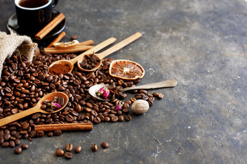 Still life with roasted coffee beans, burlap bag, spoons, dried citruses and roses, cinnamon sticks and anise stars. Ingredients for aromatic coffee, cozy coffee time. Selective focus, copy space.