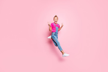 Full length body size photo of girl running fast jumping showing you double v-sign screaming with emotional facial expression wearing jeans denim t-shirt footwear isolated pastel pink color background