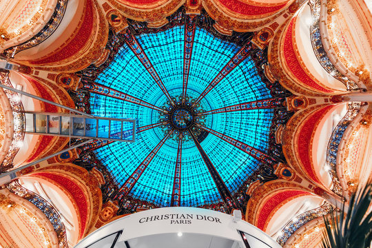 27 July 2019, Paris, France: The famous chic stained glass ceiling with beautiful patterns in the interior of the Gallery Lafayette building - a modern shopping center