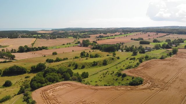 Aerial view over the idyllic Swedish hills Brosarps backar on Osterlen in Skane, Sweden. Open fields with farming crops and some cows