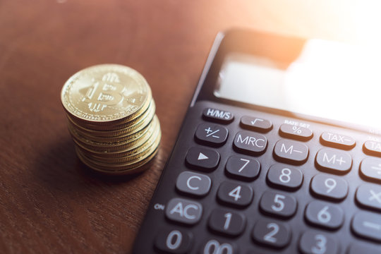 Calculator and a stack of Bitcoins coins as symbol of cryptocurrency digital money in the future blockchain.