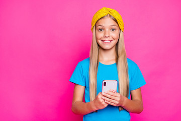 Portrait of funny funky crazy cute child positive cheerful little blogger use her phone addicted social network user wear blue clothes yellow headband isolated over fuchsia color background