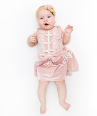 Portrait of a sweet infant wearing a pink dress, headband bow, isolated on white in studio.
