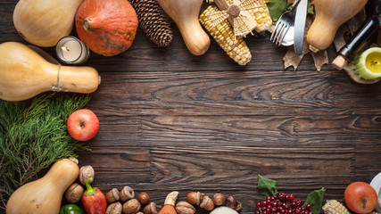 Happy Thanksgiving Day background, wooden table decorated with pumpkins, wine, corncob, candles and autumn leaves. The concept of harvest and autumn celebration.