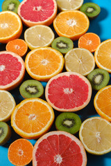 Fototapeta premium Fresh summer fruits on blue background. Healthy food concept. Flat lay. Tropical summer mix grapefruit, orange, mandarin, kiwi, lemon