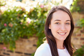 Portrait Of Smiling Woman At Home In Garden Against Flaring Sun