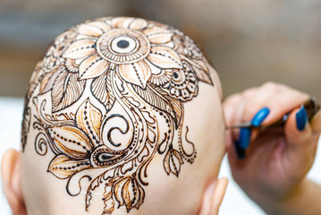 Drawing process of henna mehndi ornament on womans head