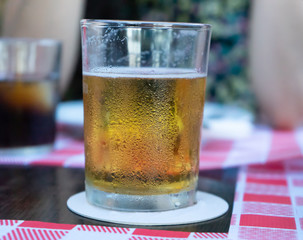 Crystal Glass of refreshing draft beer with a friend in a table of a pub. Lager in a bar terrace with company. Thirsty drunk person drinking alcohol in summertime outside