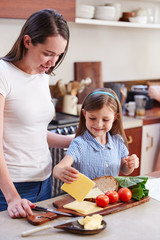 Same Sex Female Couple With Daughter Preparing School Lunchbox At Home Together