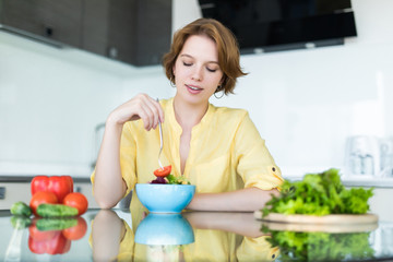 Woman making salad in kitchen. Healthy eating lifestyle concept with beautiful young woman cooking in her kitchen.