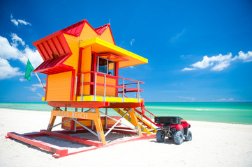 Vibrant sunny view lifeguard tower painted bright colors under blue sky on South Beach, Miami,...