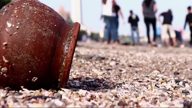 Low angle shot of pot lying on beach. people cleaning the beach. close up of trash on beach. Dadar, Mumbai. Trash on sand. Beach clean up in India.