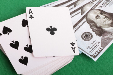 Cards and paper dollars on a table with green cloth