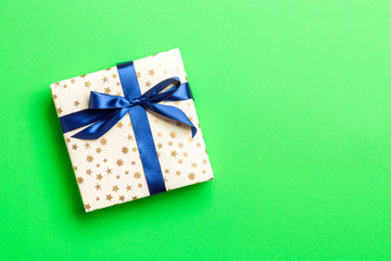 wrapped Christmas or other holiday handmade present in paper with blue ribbon on green background. Present box, decoration of gift on colored table, top view with copy space