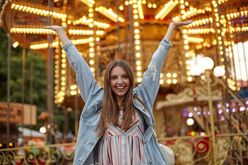 Outdoor photo of pretty young female with long brown hair looking to camera with sincere smile and...
