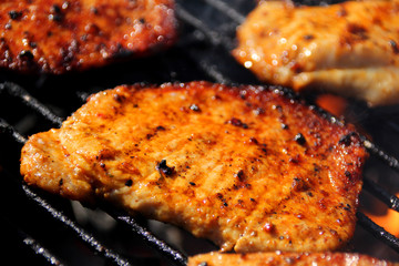beautiful grilled roasted meat steaks grilled on the street on a black metal grill on burning coals, picnic concept, close-up