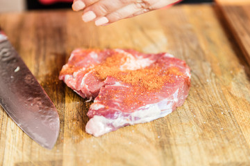 Close-up of chef spicing meat.
