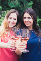 Two happy girls cheering with rose wine.