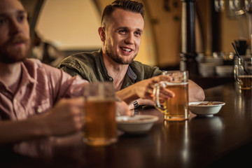 Cheerful friends drinking draft beer in a pub