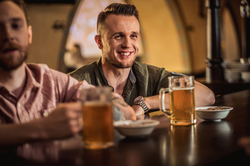 Cheerful friends drinking draft beer in a pub