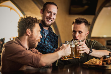Friends drinking draft beer and watching tv in a pub