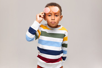 Isolated image of trendy handsome black boy having curious or suspicious facial expression, taking...
