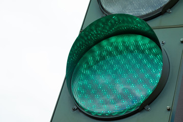 Close-up of green light of traffic-light against white sky