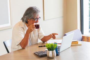 Senior man are working at home using computers and laptops, with the internet communicating online with other people.