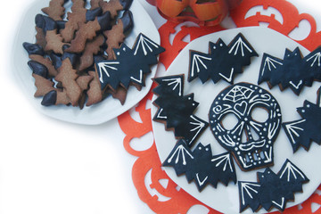 Halloween cookies in shape of a skull and bat on a plate isolated on white background. Halloween sweet food