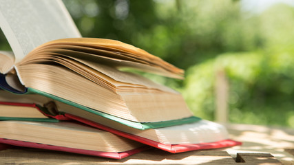 Studying in summer concept. Open book on a wooden table in a garden, sunny summer day